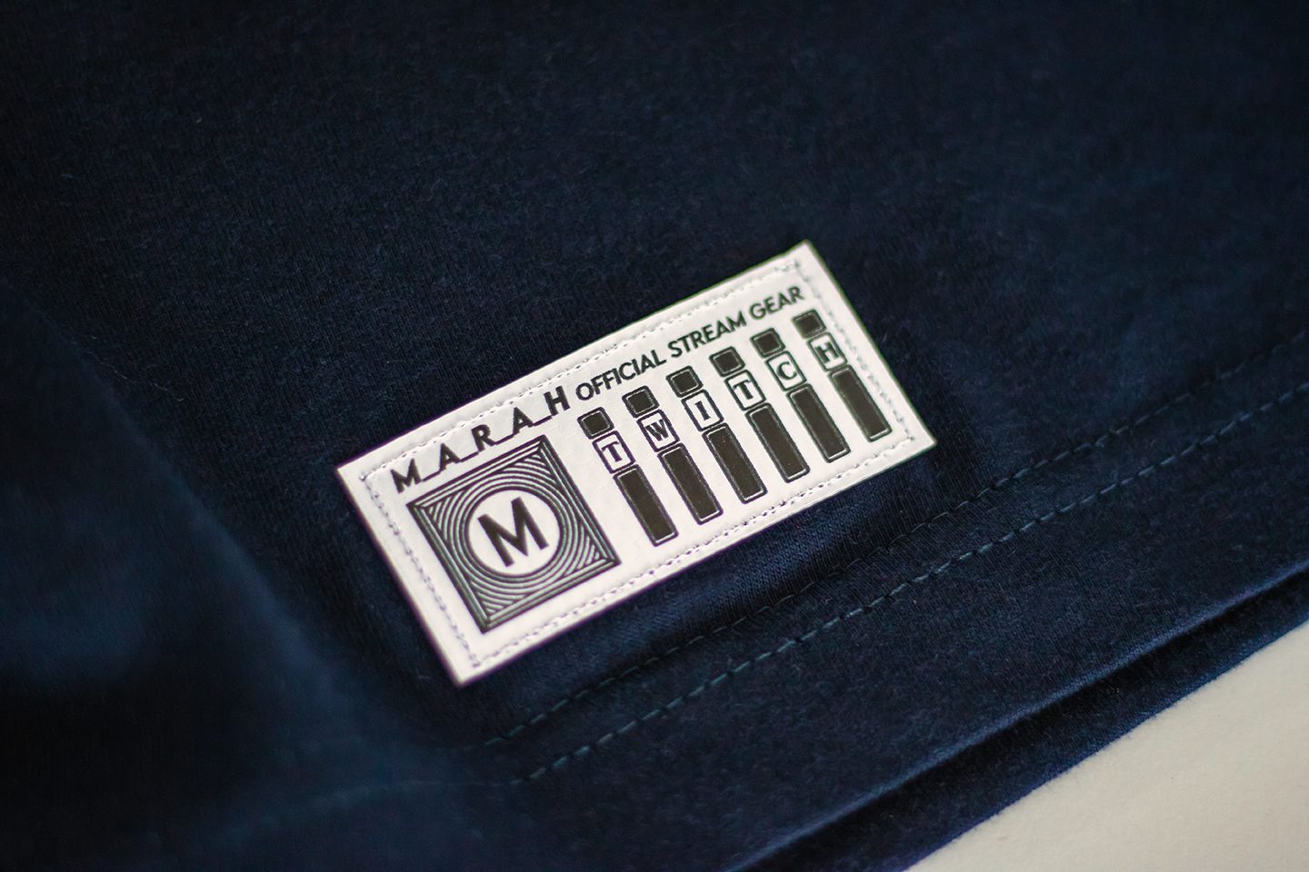 Navyblaues Shirt mit aufgenähtem schwarz-weißen MARAH Official Stream Gear Twitch-Label