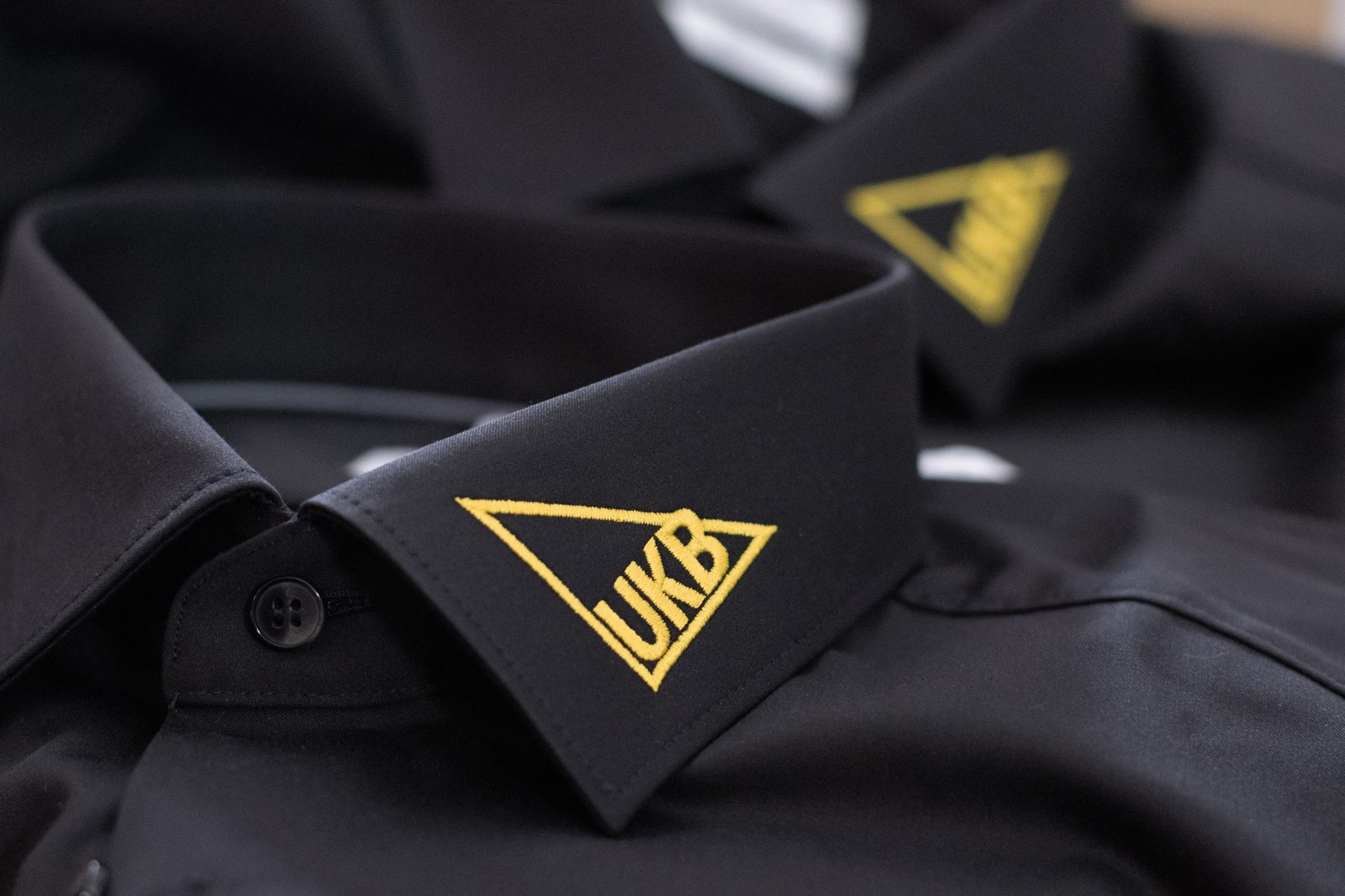 Schwarze Business-Hemden mit gelb gesticktem UKB-Logo am Kragen