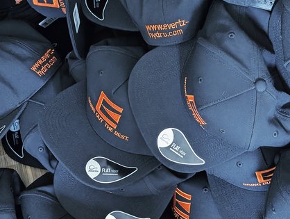 Bestickte Flat Caps mit orangefarbenem Logo und Schriftzügen für Evertz aus Betzdorf