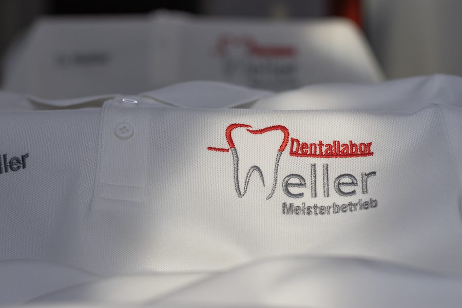Weißes Poloshirt mit gesticktem Logo eines Dentallabors und Namensstickerei