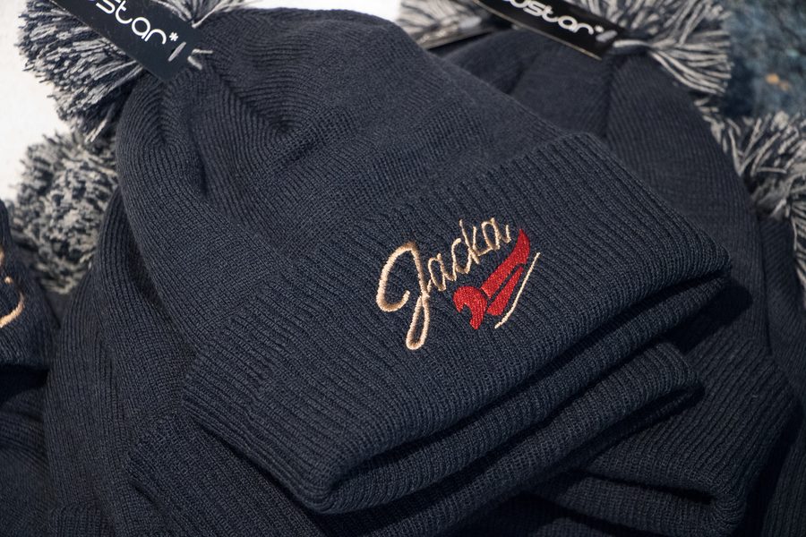 Dunkelblaue Bommelmützen mit gesticktem Logo in Beige und Rot
