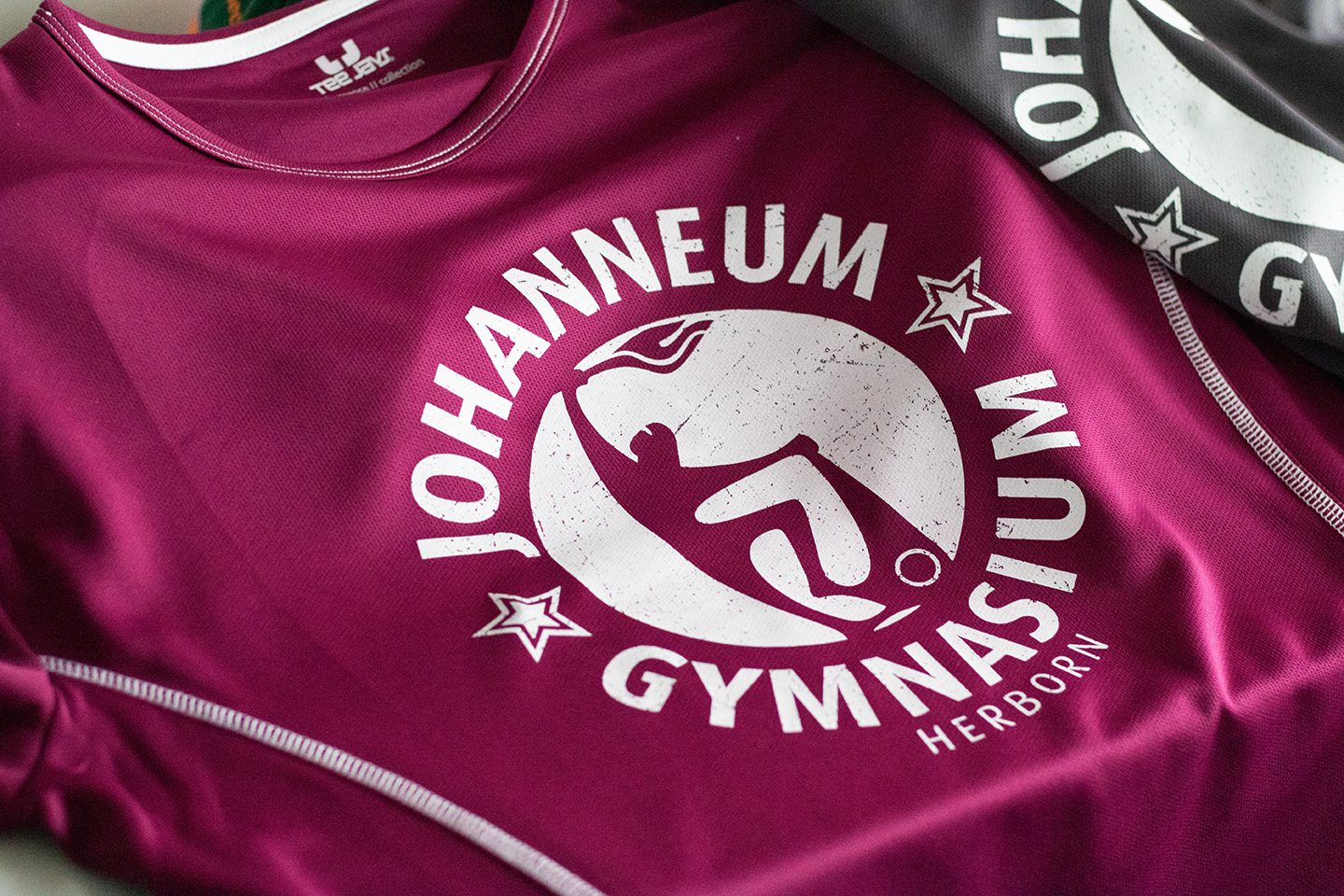 Beere- und schwarzfarbene Schul-Sportshirts mit bedrucktem Logo Johanneum Gymnasium Herborn